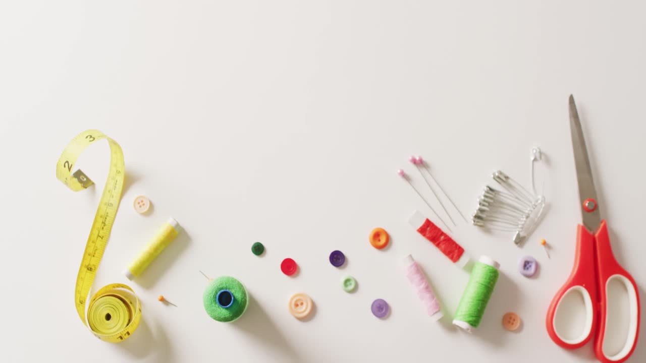 vídeo de tijeras, cinta métrica, botones, alfileres y bobinas de algodón sobre fondo blanco con espacio para copiar