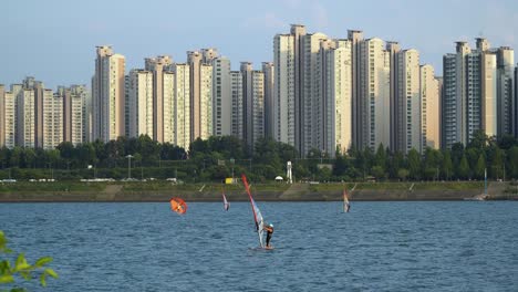 people windsurfing on han river at sunset on complex high apartment background, ttukseom surfing club, daytime static