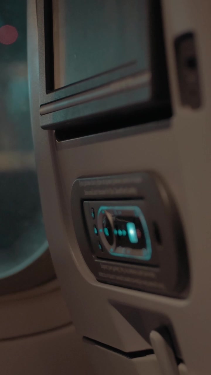 Vista interna di un aereo con monitor sul sedile e luci notturne nell'oblò
