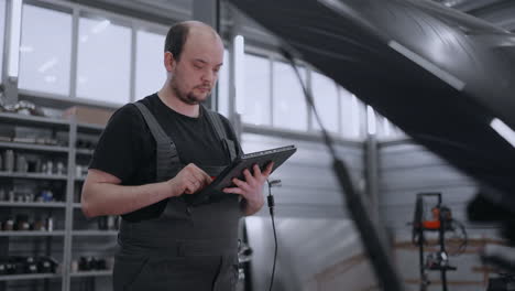 mecánico automotriz trabajando con una herramienta de diagnóstico de automóviles en un taller de reparación. el gerente de servicio de automóviles o mecánico utiliza una tableta con un software de diagnóstico interactivo futurista.