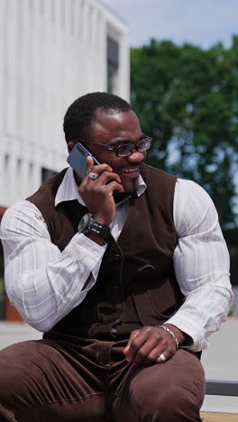 waist up portrait of the attractive man with well groomed hairstyle and beard using his smartphone outdoor. having nice and interesting appearance. male speaking on his mobile phone and laughing. vertical video