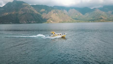 drone aerial tracking a boat driving fast in lake atitlan, guatemala