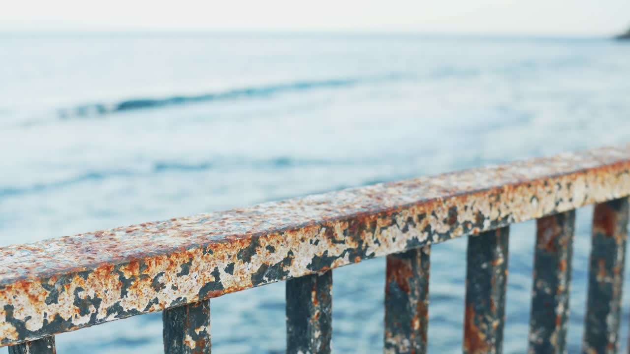 Female putting hands on rusted metal railing on waterfront, depression concept