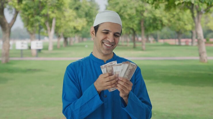 hombre musulmán feliz contando dinero en el parque