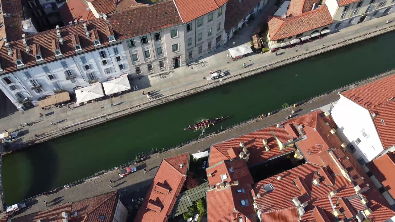 Persone remano sui Navigli circondati da architettura maestosa, vista aerea.