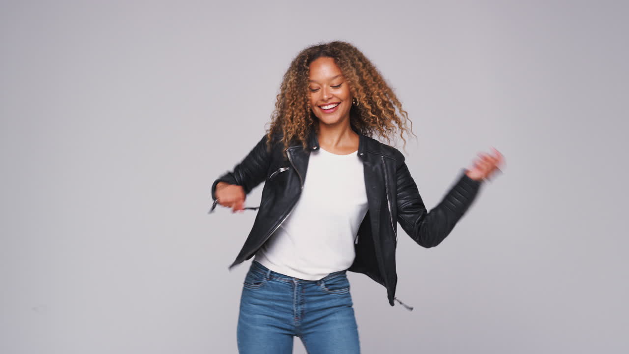 Wide Angle Studio Shot Of Young Woman Wearing Leather Jacket Dancing In Slow Motion