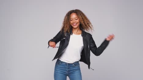 wide angle studio shot of young woman wearing leather jacket dancing in slow motion