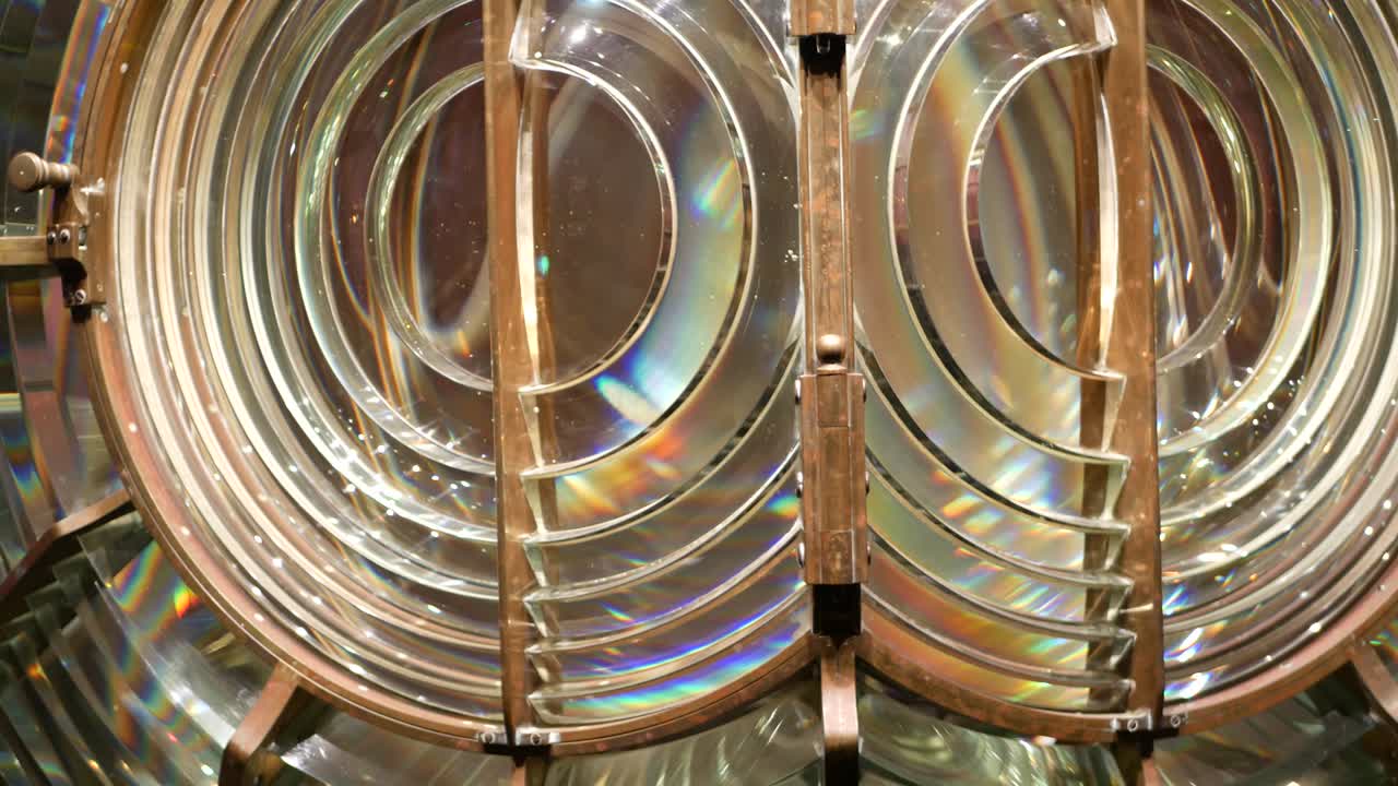 lente de fresnel con estructura de bronce, torre de faro náutico. detalle de la linterna de vidrio con espectro de arco iris. sistema de lámparas y lentes para servir como ayuda de navegación. viejo faro de búsqueda de mar.