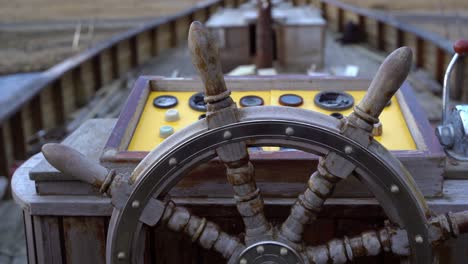 old wooden ship wheel and yellow control panel dashboard, close up