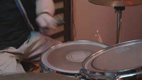 unrecognizable male musician playing drums during a band rehearsal in recording studio 1