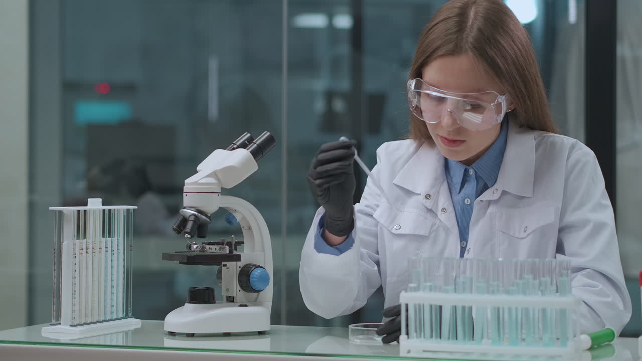 estudiante de laboratorio médico mujer joven está trabajando con tubos de ensayo con productos químicos y análisis médico haciendo diapositivas de microscopio para investigación y exploración