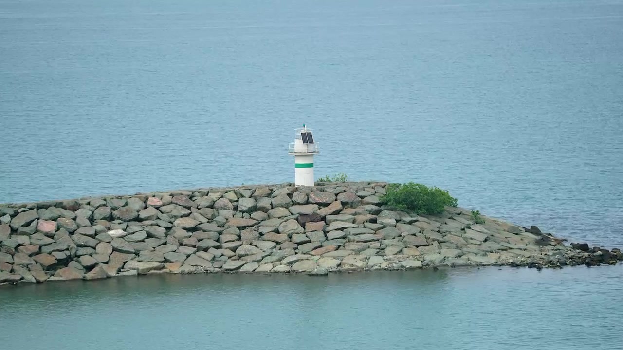 Lille fyrtårn på en stenet bølgebryder i havet