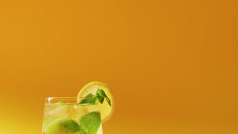 close up of drink with lemon on yellow background