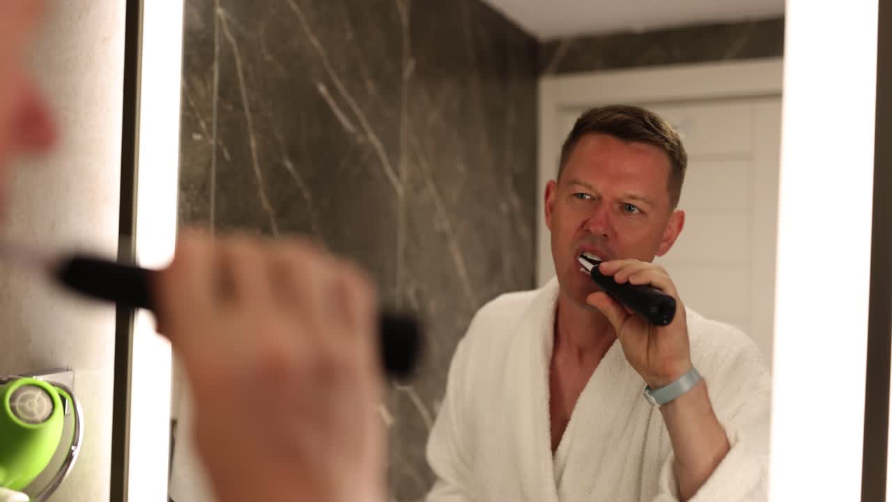 Man in a bathrobe brushing teeth in the bathroom