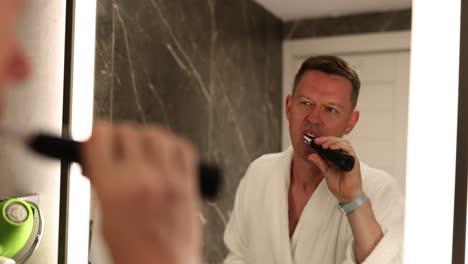 man in a bathrobe brushing teeth in the bathroom