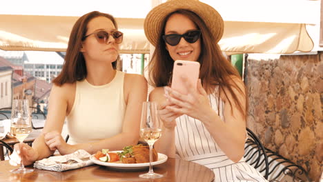 dos mujeres tomando una selfie mientras tienen un brunch de champán al aire libre