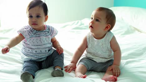 Two-cute-baby-girls-sitting-on-bed