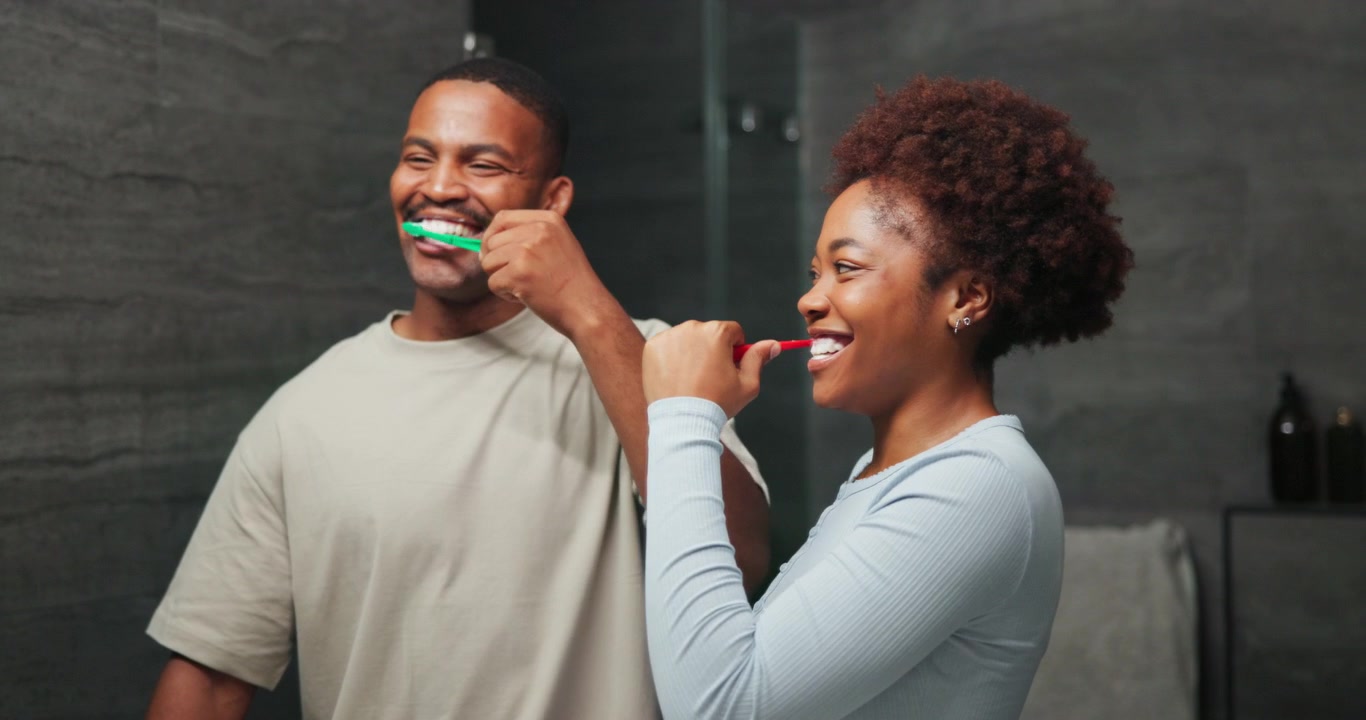 Coppia felice che si lava i denti insieme in un bagno moderno