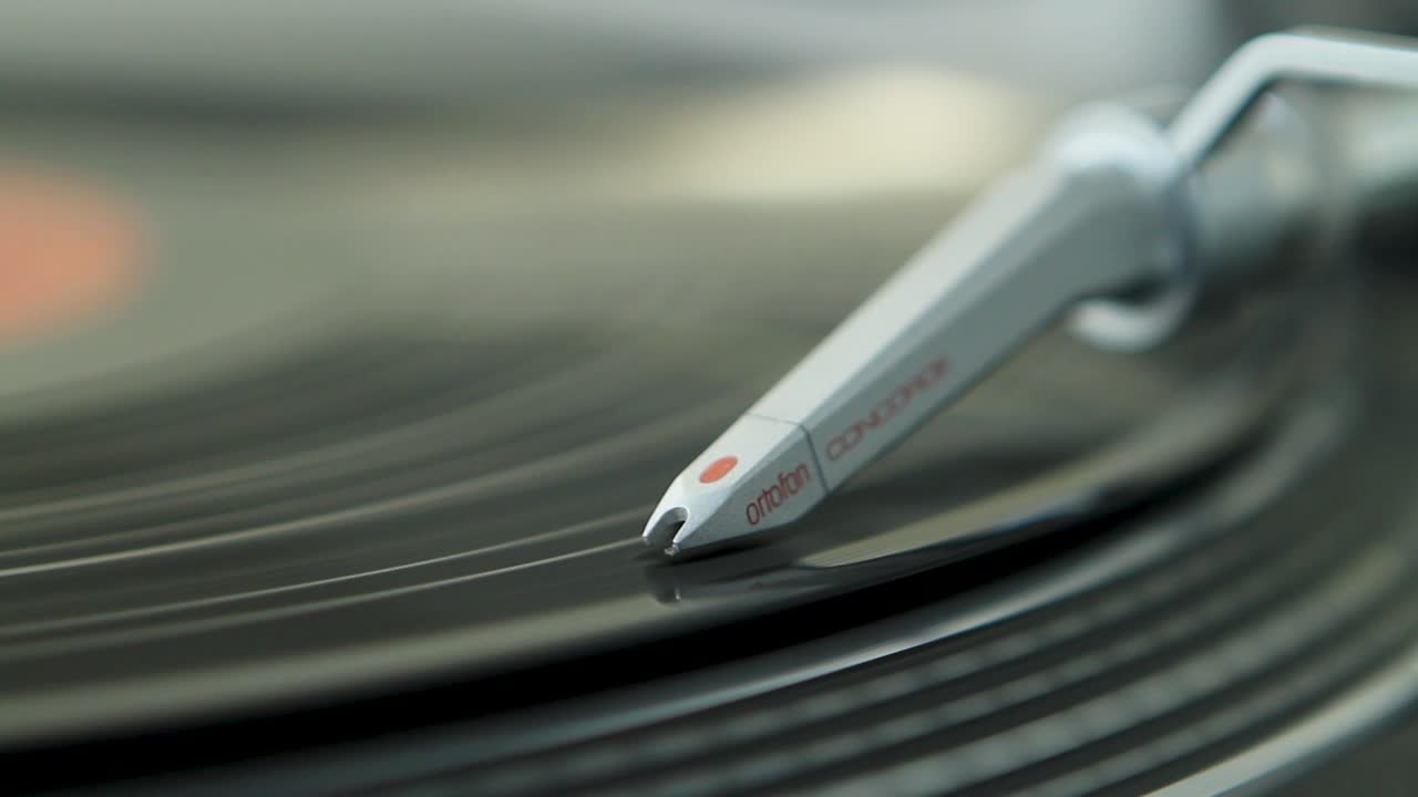 A close-up of a turntable needle playing a vinyl record, capturing the grooves in detail