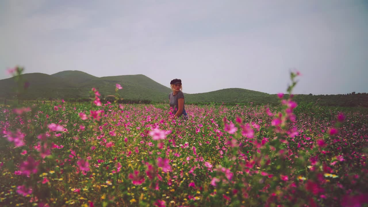 이탈리아 투스카니의 무성한 화려한 꽃밭에 앉아 있는 젊은 브루네트 여성의 4k uhd 시네마그래프