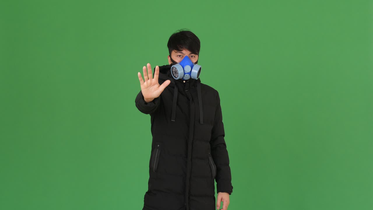 Young Man Wearing Pollution Mask Showing Stop Sign, Green Screen