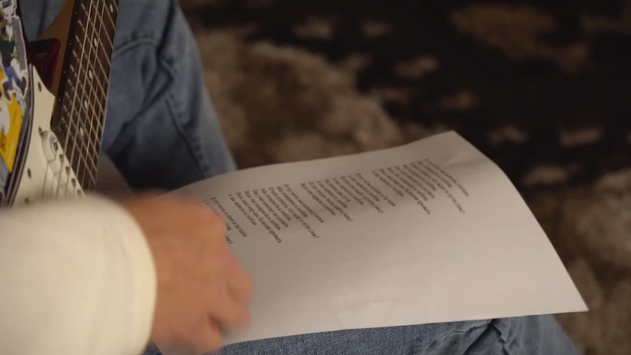 persona tocando la guitarra y mirando las partituras