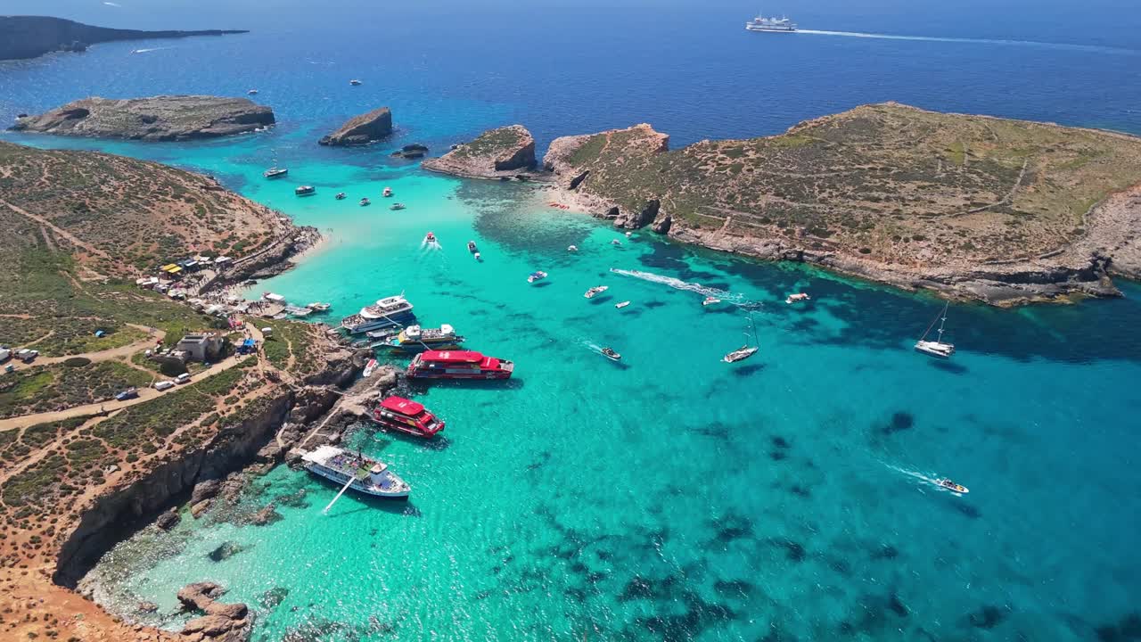 Malta, Comino'daki Mavi Lagün, turkuaz kristal berraklığında sulara, kayalık kıyılara ve Cominotto adası yakınında demirli teknelere sahiptir; Akdeniz'de güneşli bir günde yukarıdan görünüm.