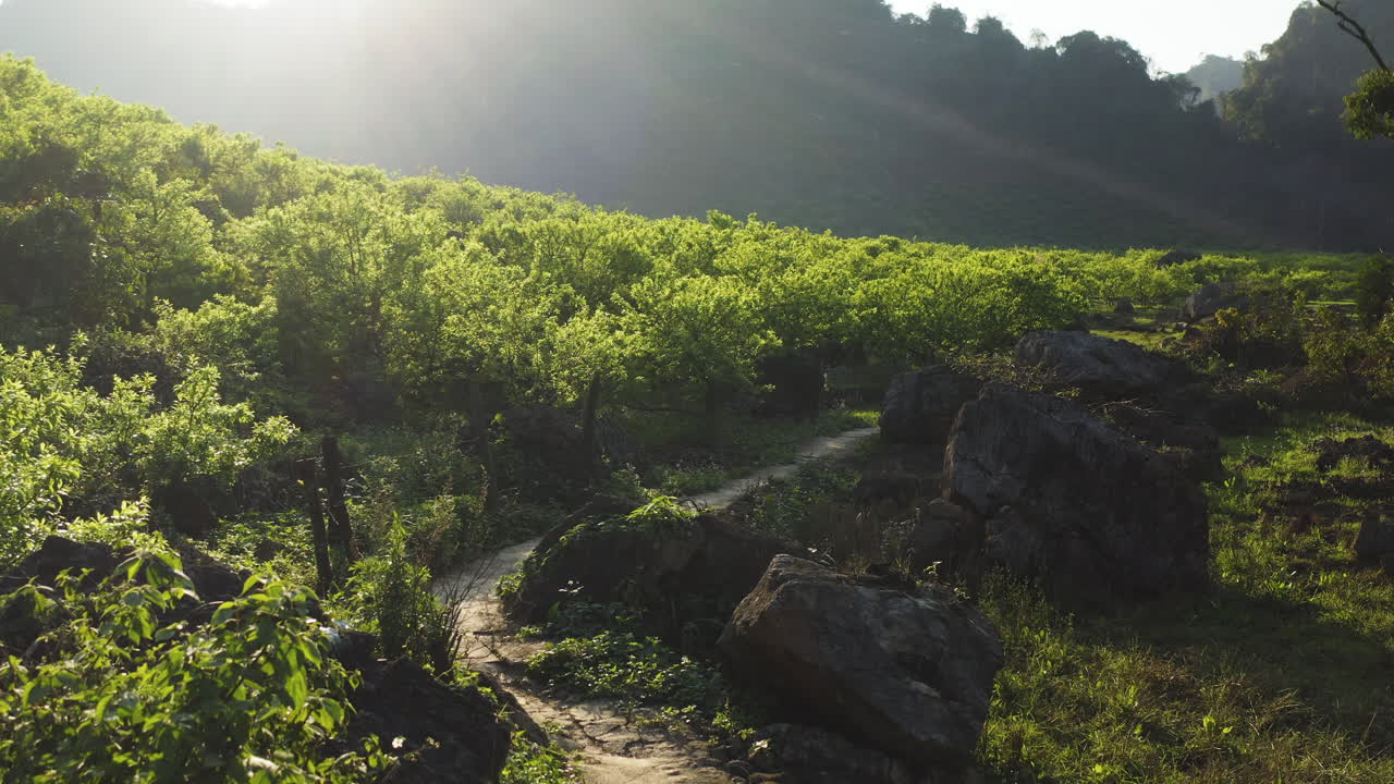 Drone tracks a dirt path winding through trees, rocks, and valleys in Mộc Châu’s Na Ka region