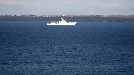 Telephoto-shot-of-a-Royal-Navy-fisheries-patrol-ship-driving-through-rough-seas-into-the-inlet-of-Broadbay-near-Stornoway,-part-of-the-Outer-Hebrides-of-Scotland