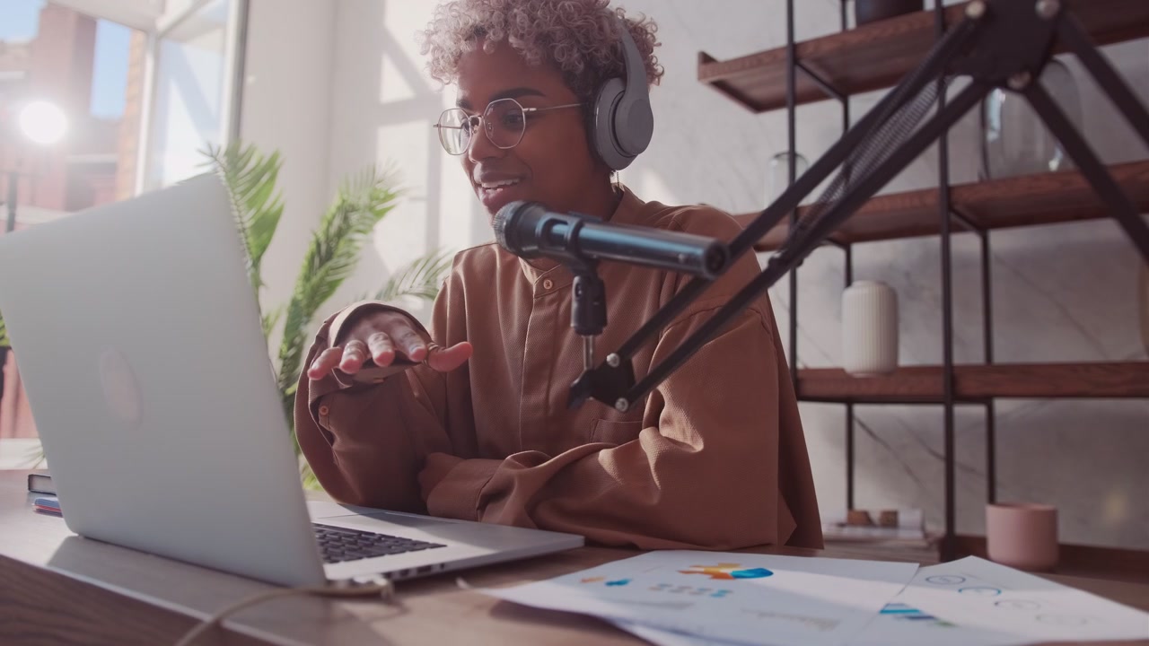 Afrikanische Frau veranstaltet einen Online-Mode-Stream, trägt Kopfhörer und Mikrofon.