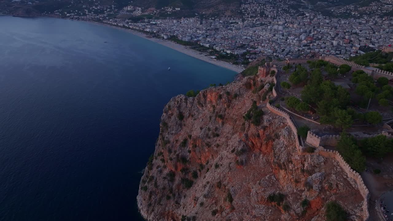 Obloha při západu slunce za hradem Alanya a loď na Středozemním moři.
