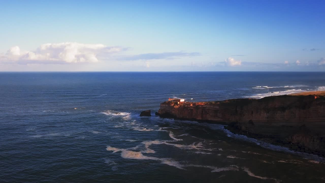 An iconic place on the Atlantic coast, the Mecca of big-wave surfing. View of Nazare's lighthouse in Zon North Canyon, place with the biggest waves in Europe, Nazare, Portugal