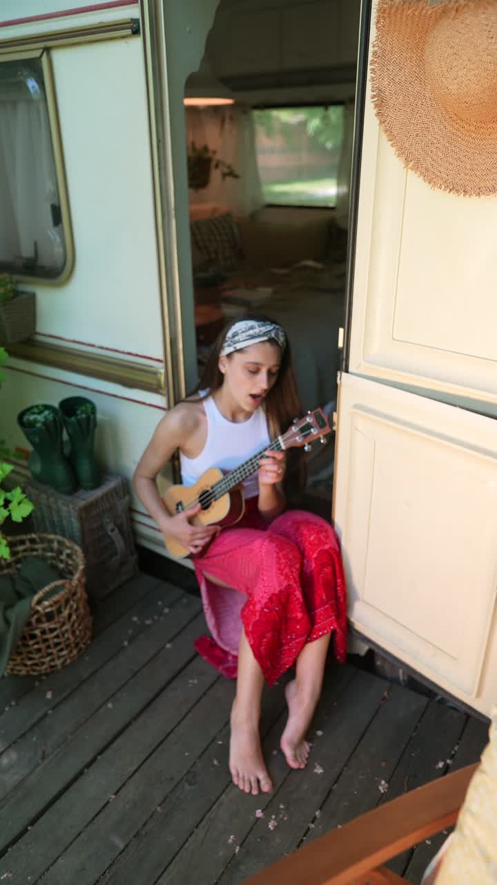 mujer tocando el ukulele en un patio de campamento