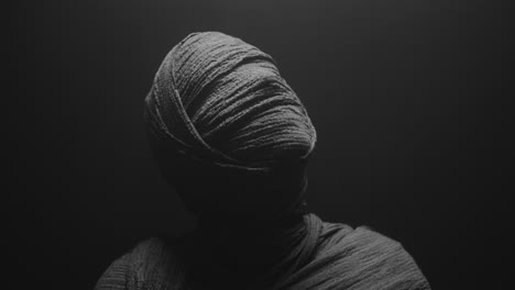 a mummy of a woman on a dark backdrop rises her head