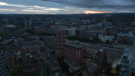 establishing drone shot of leeds city centre around leeds train station in low light and orange sunset in distance west yorkshire uk