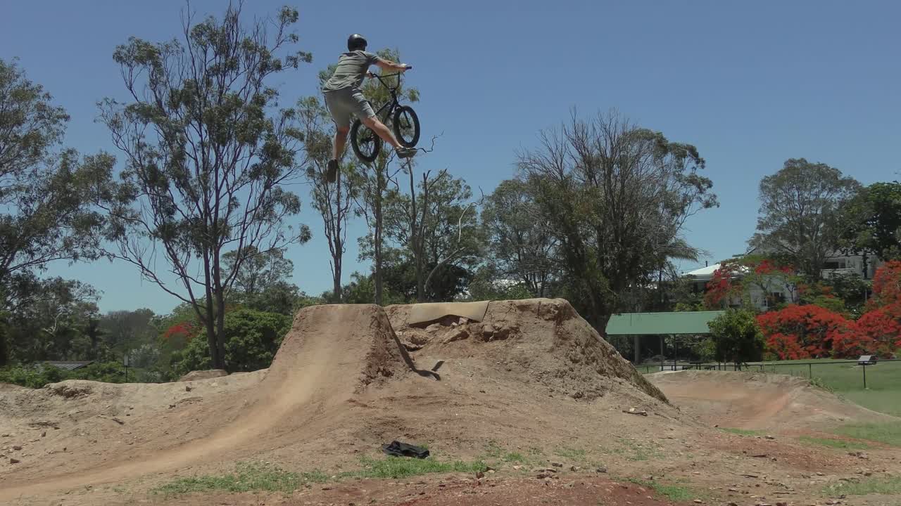 Dynamic 4K BMX footage of a superman trick over a dirt jump, shot from behind. Ideal for commercials, sports promos, or vlogs. 4K, 9s, model-released. License now!