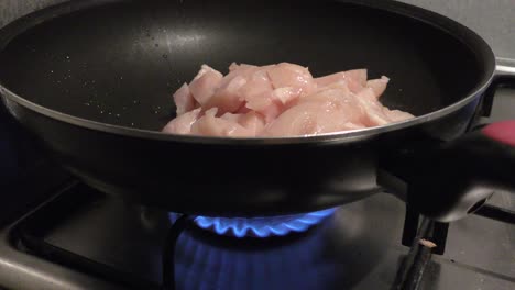 fuego de gas ardiendo bajo una sartén llena de carne de pollo saludable