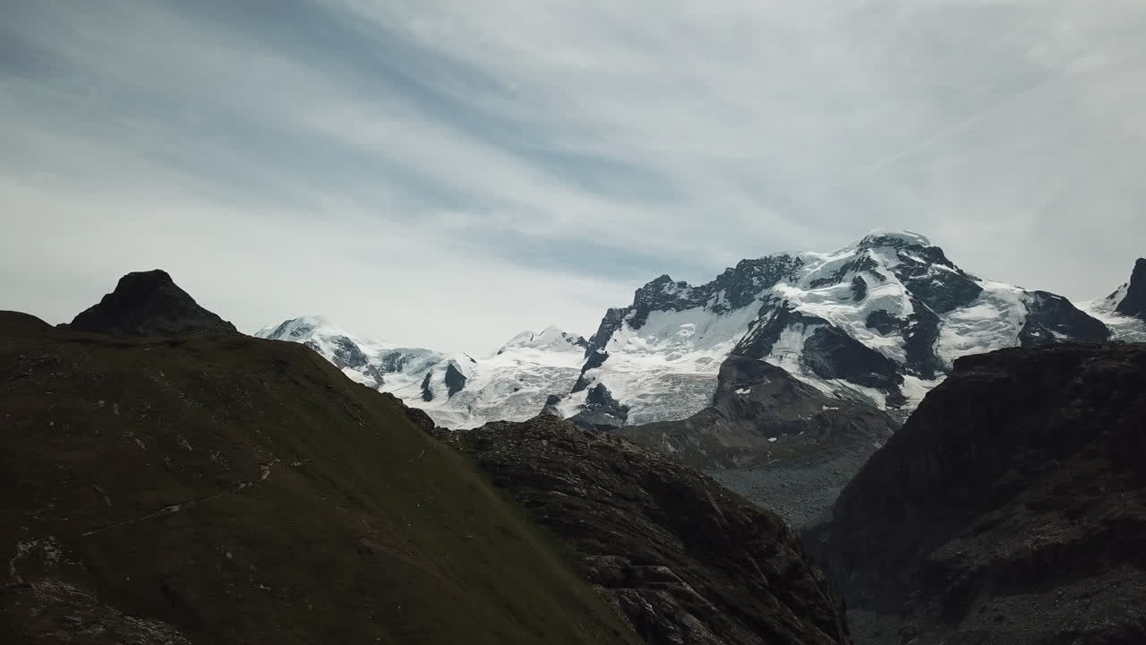 vista de drones de las cumbres en los alpes suizos, nieve a gran altura, cielo nublado, montañas