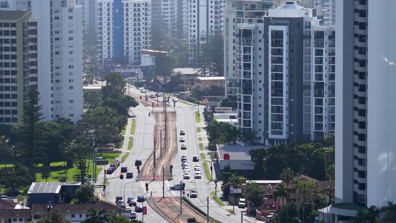 Drone footage captures bustling traffic amidst skyscrapers on a sunny day in Gold Coast, Australia, highlighting urban life and movement
