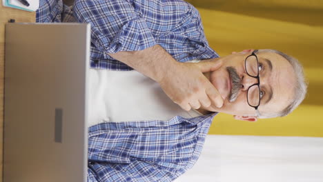 Vertical-video-of-Old-man-looking-at-laptop-is-thoughtful.