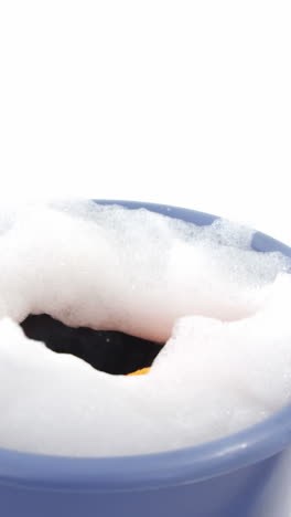 Cleaning sponge falling in to bucket of soap suds