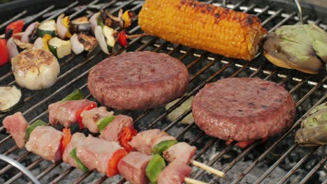 grilled burgers, corn on the cob, and assorted vegetables on a grill