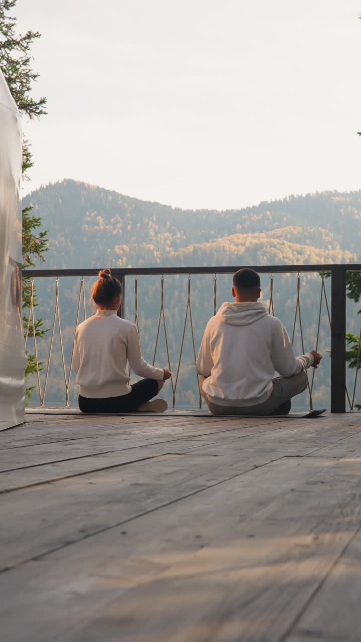 사람들은 해가 뜨면 둥근 집 테라스에서 명상합니다. 여자와 남자는 아침 일찍 롯스 포즈에 함께 앉아 마음에 대한 휴식 연습을 즐니다.