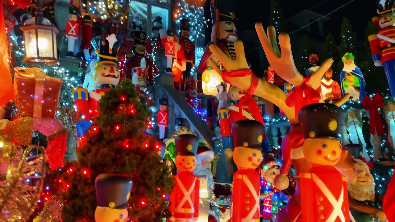 Decoraciones navideñas de cascanueces y renos con luces festivas. Primer plano de cascanueces de soldado de plástico y figuras de renos iluminadas por luces de colores