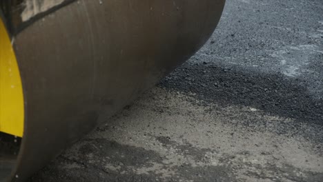 process of asphalting road construction infrastructure by compressing, compacting, leveling and smoothing the asphalt road surface using a tandem roller