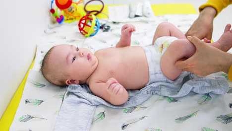 baby's being dressed after pediatrician's examination. mother is putting clothes on her baby son. close up.