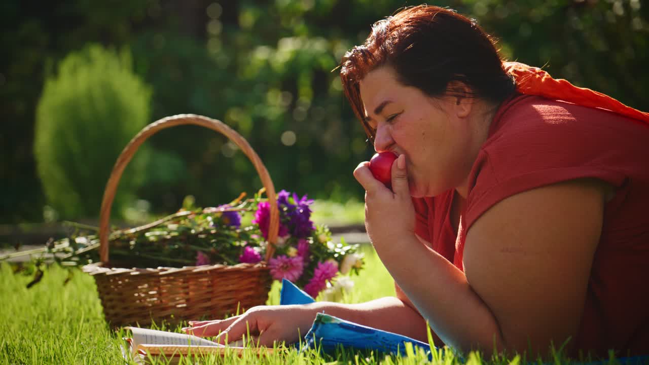 Ein freudiger Moment der Entspannung in der Natur: Genieße einen frischen Apfel, umgeben von bunten Blumen und einem gemütlichen Picknick an einem sonnigen Tag