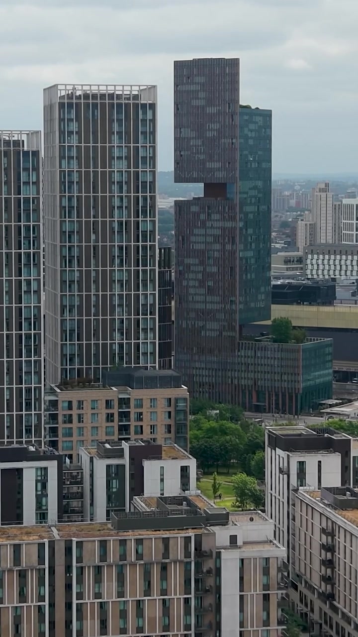 Giardini loft Manhattan a Stratford, Londra, mentre un drone vola verso le torri gemelle con grattacieli più ampi dell'East London, inclusa lo skyline del distretto di Stratford sotto cieli coperti. Formato verticale.