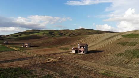 Drohnenfliegen-Verlassen-Bauernhöfe-Und-Enthüllen-Zur-Goldenen-Stunde-Das-Hügelpanorama-Der-Landschaft-Apuliens