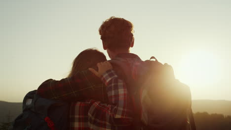 una pareja romántica disfrutando de la puesta de sol en las montañas.